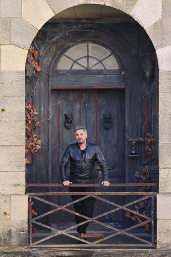 Portrait d'Olivier Minne devant la porte du Manoir